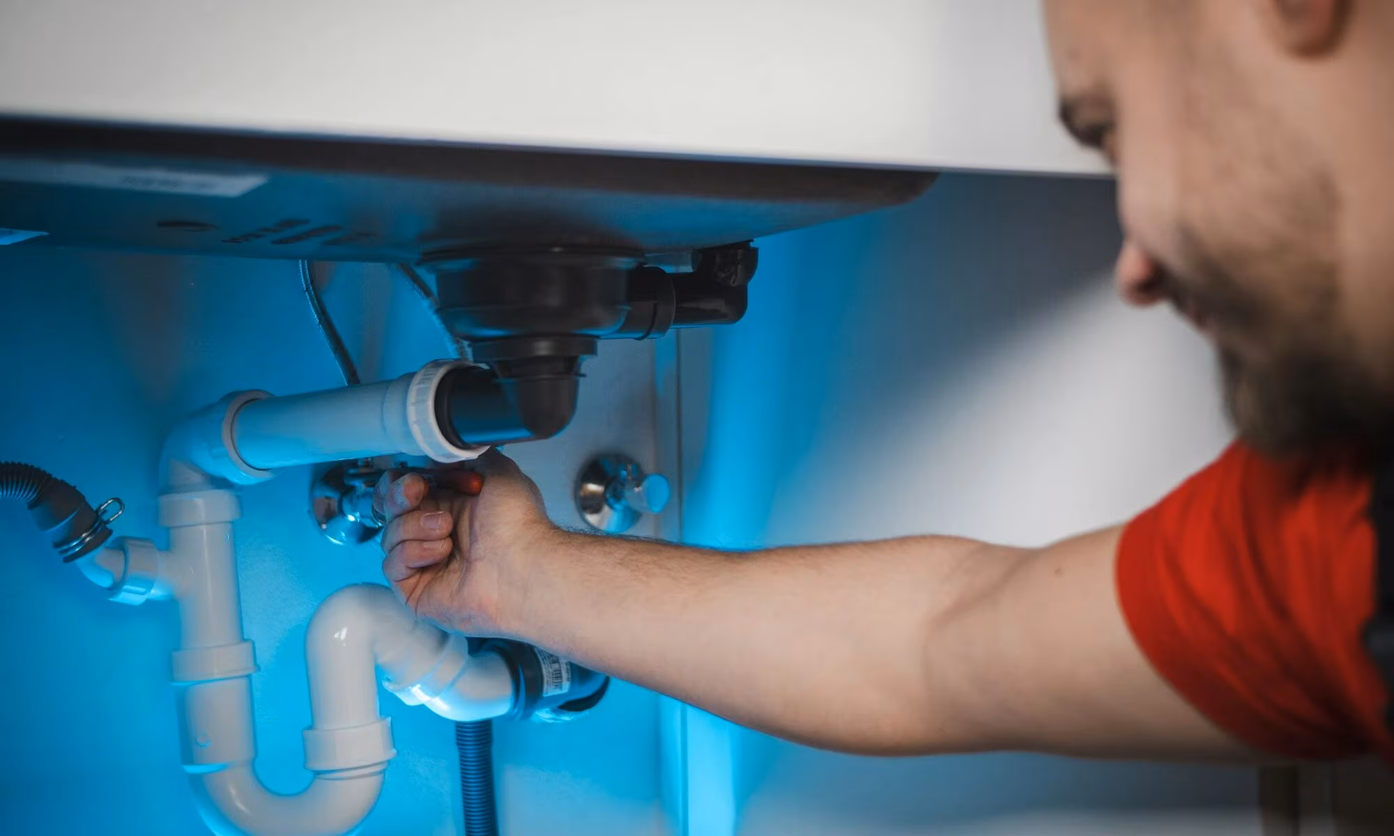Plumber fitting pipework under a sink